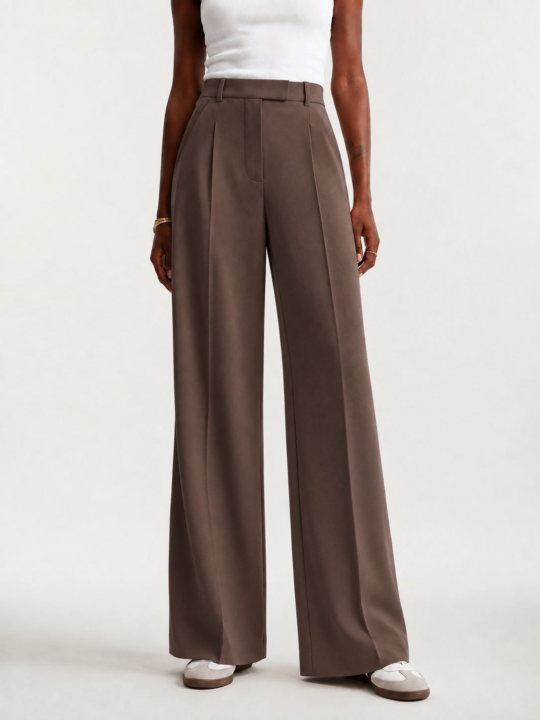 Pantalón marrón topo de pierna ancha mostrado de frente con zapatillas blancas.