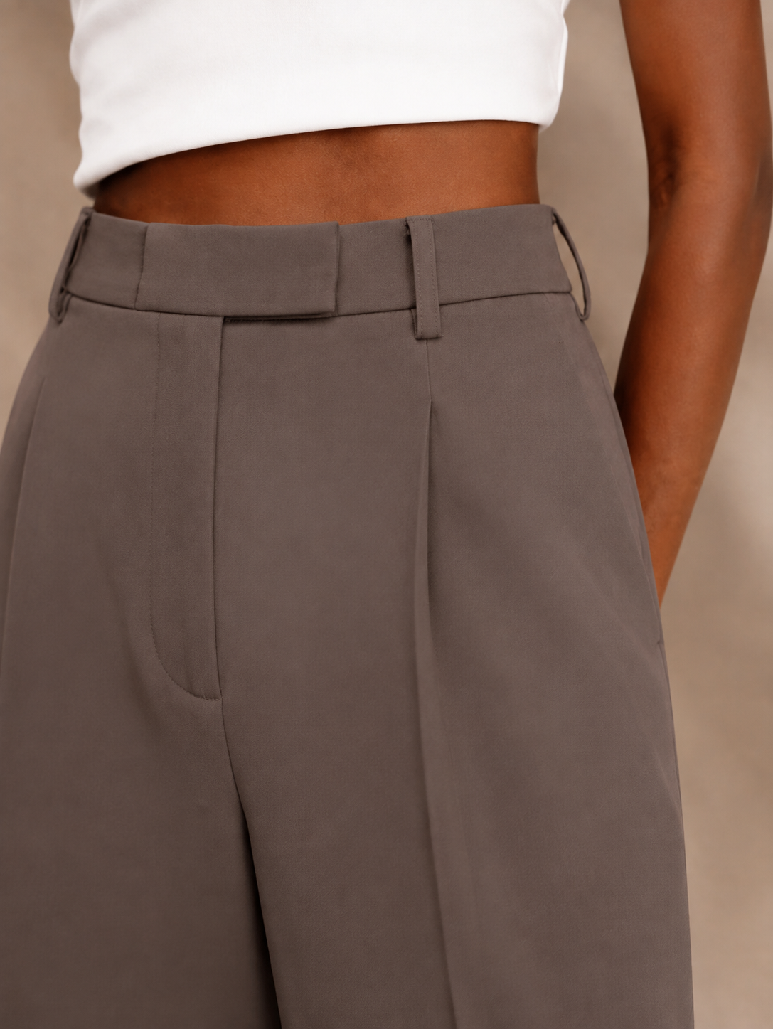 Primer plano del pantalón gris topo que muestra la pinza frontal y el bolsillo lateral.