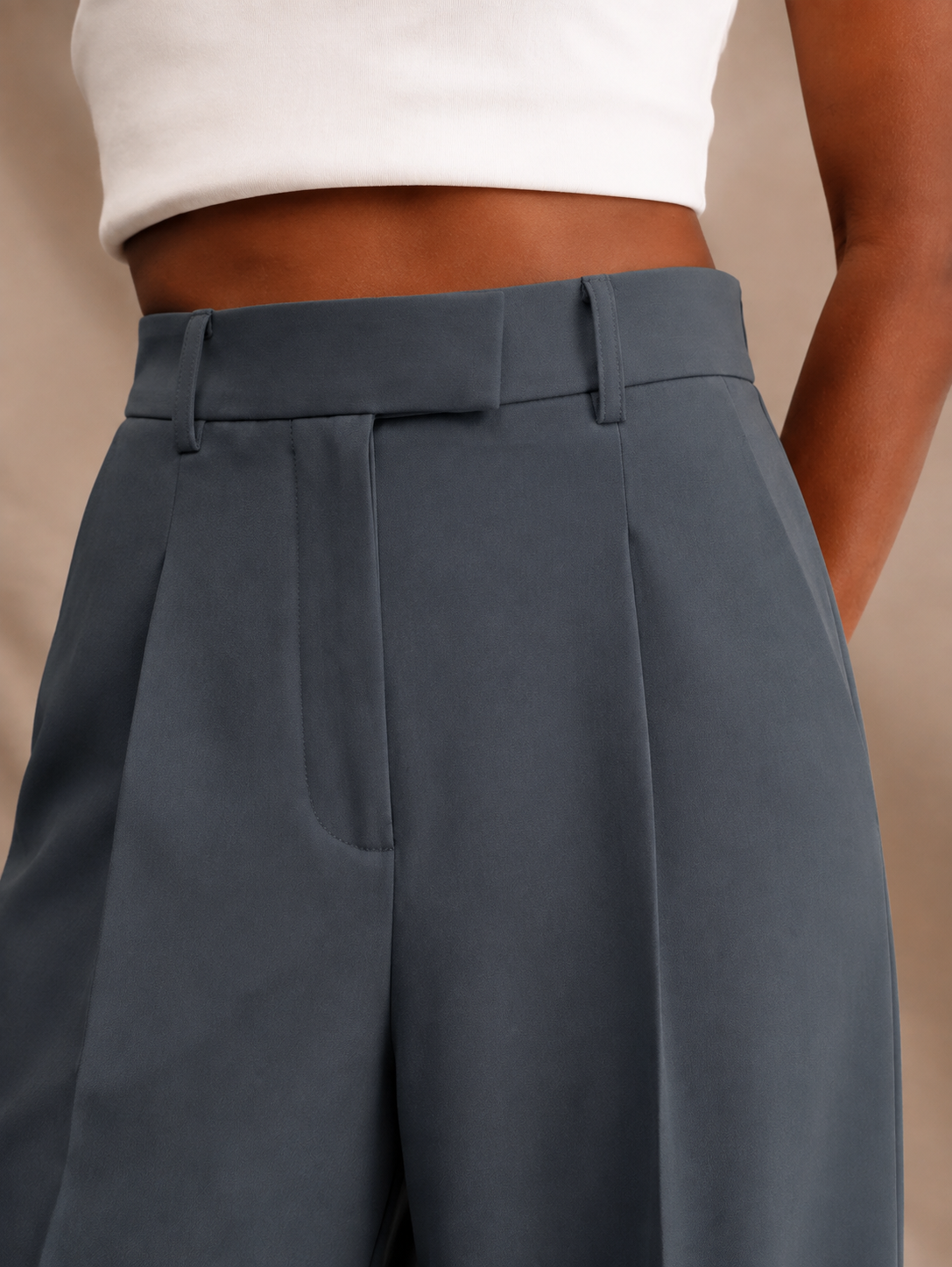 Detalle en ángulo del pantalón azul grisáceo con cintura alta y bolsillo lateral.