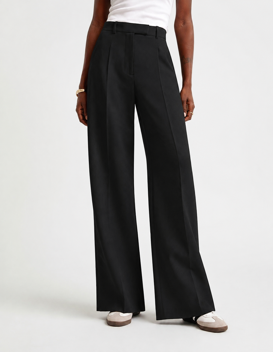 Pantalón negro de tiro alto y pierna ancha mostrado de cuerpo entero con zapatillas.