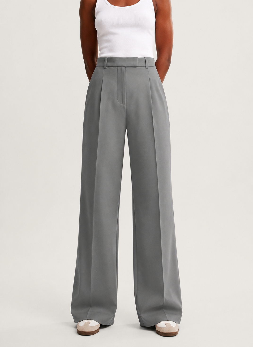 Pantalón gris de tiro alto y pierna muy ancha mostrado de frente con las manos en los bolsillos.