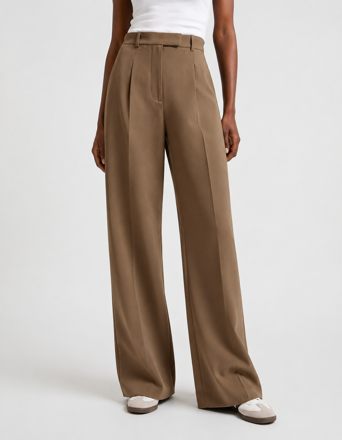 Pantalón de tiro alto marrón con corte amplio y pinzas delanteras, combinado con zapatillas claras.