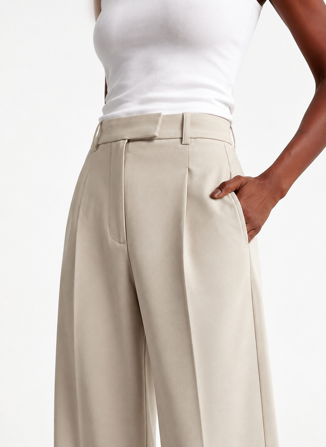 Vista cercana en ángulo del pantalón marfil con trabillas para cinturón y bolsillo lateral.