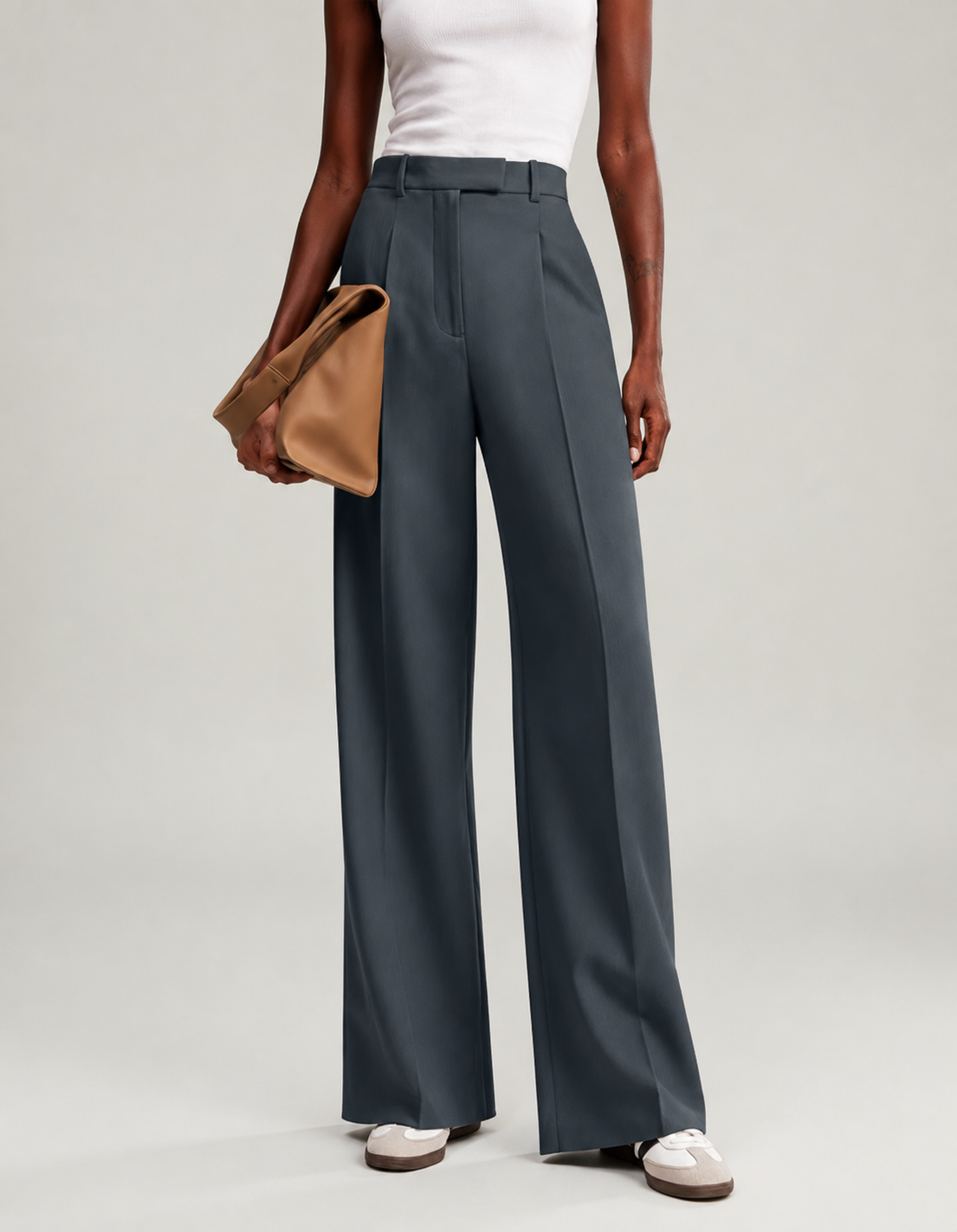 Pantalón de pierna ancha azul grisáceo mostrado de cuerpo entero, acompañado de un bolso de mano.