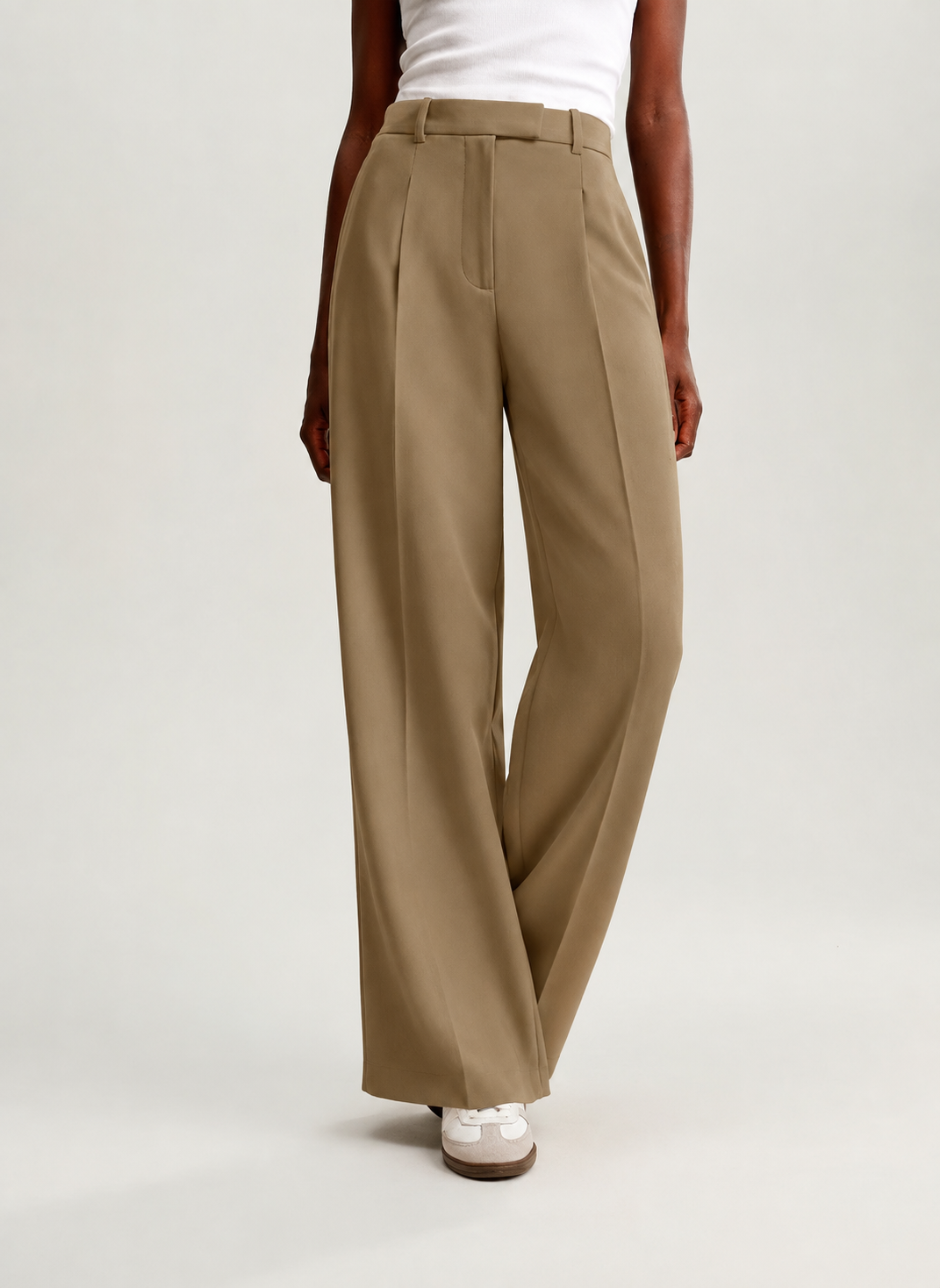 Pantalón marrón claro de pierna ancha en una pose cruzada que resalta su caída fluida.