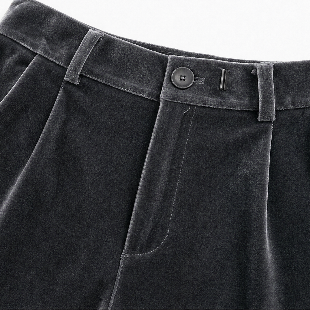 Detalle de la cintura alta del pantalón gris oscuro, con botón, cierre, trabillas y bolsillo lateral.
