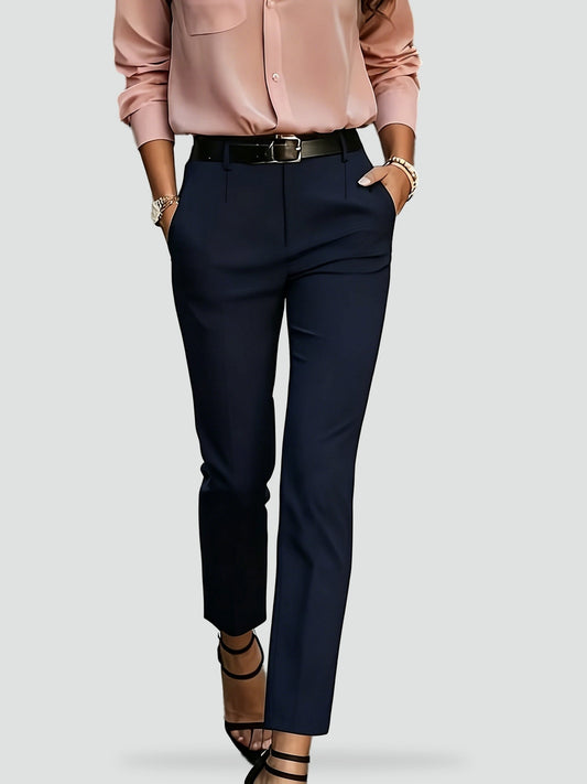 Pantalón de vestir azul marino de tiro alto y corte entallado, combinado con blusa rosa y cinturón negro.