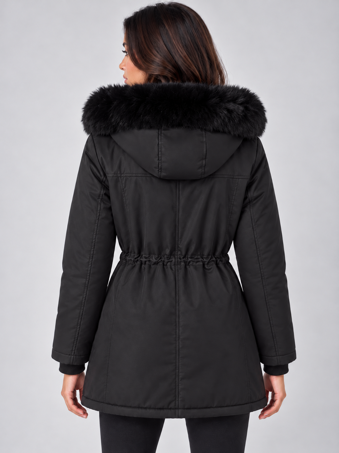 Vista posterior de la parka negra, con capucha ribeteada de pelo sintético, largo a la cadera y cintura fruncida ajustable.