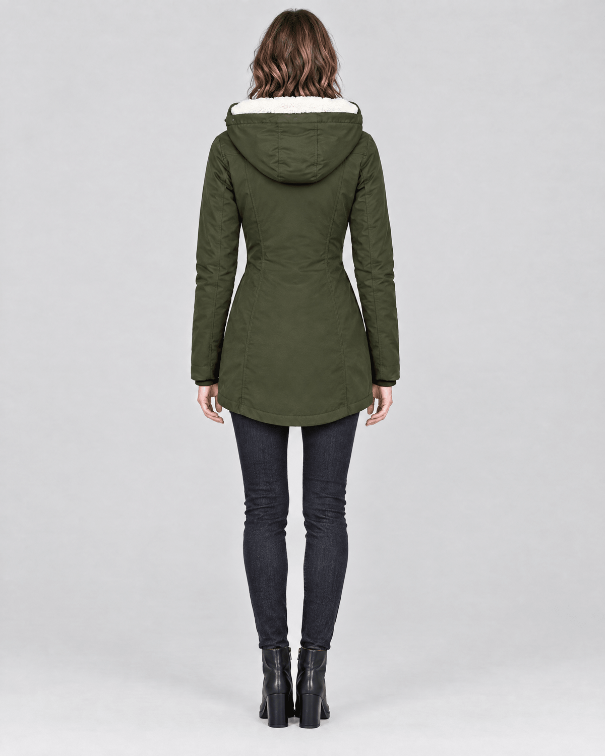Vista posterior de una parka verde oliva entallada, con capucha y bajo redondeado.