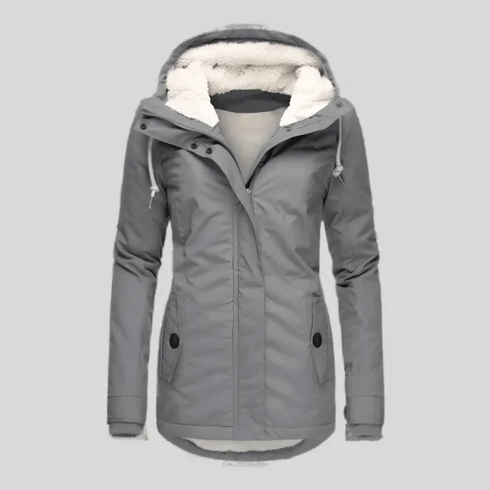 Parka gris presentada de frente sin modelo, con capucha abierta, forro cálido visible y bolsillos laterales con solapa.