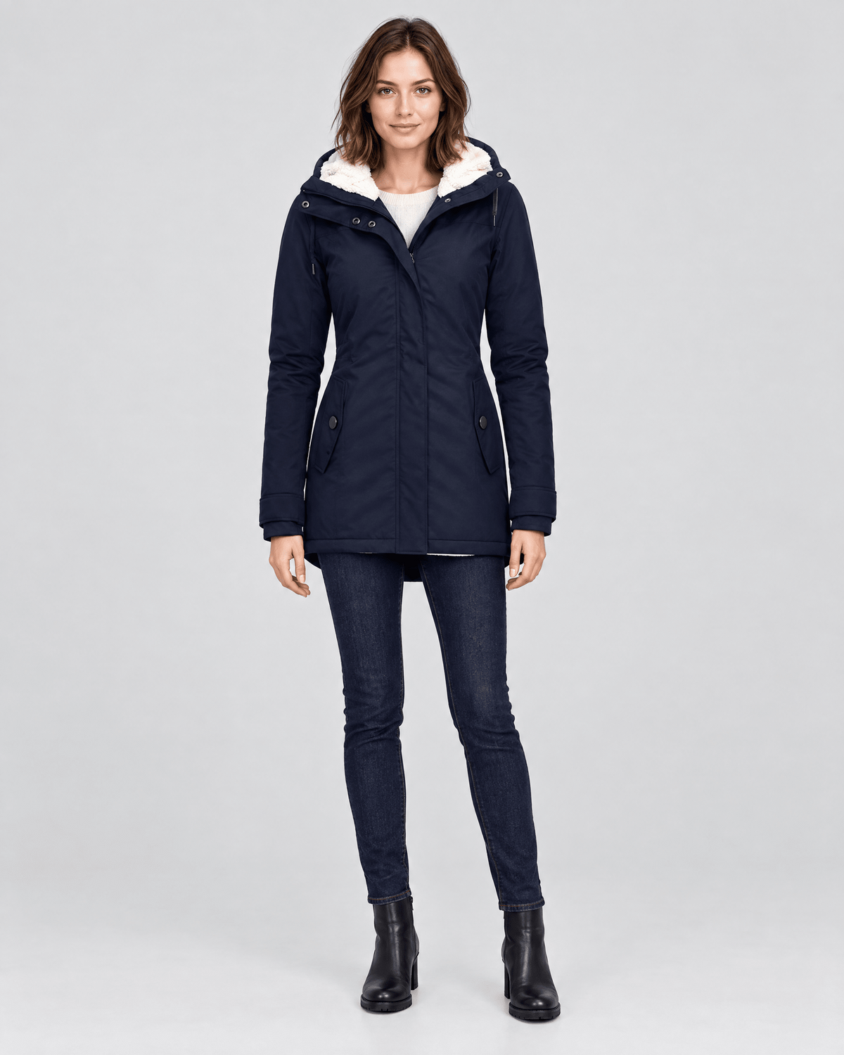 Parka azul marino entallada con capucha forrada y bolsillos laterales, mostrada de frente sobre un conjunto informal.