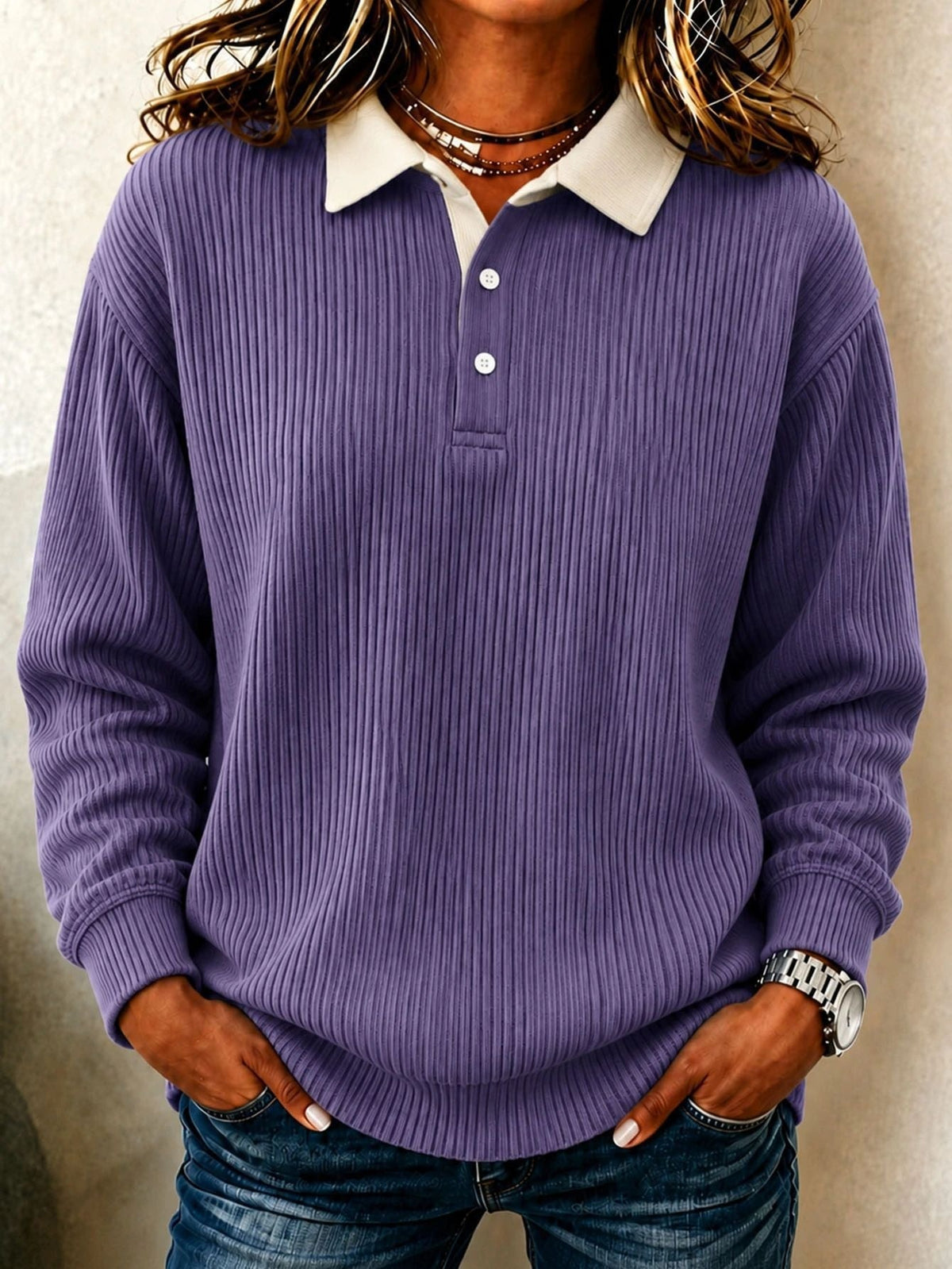 Polo morado de manga larga con relieve acanalado, cuello crema en contraste y dos botones visibles.