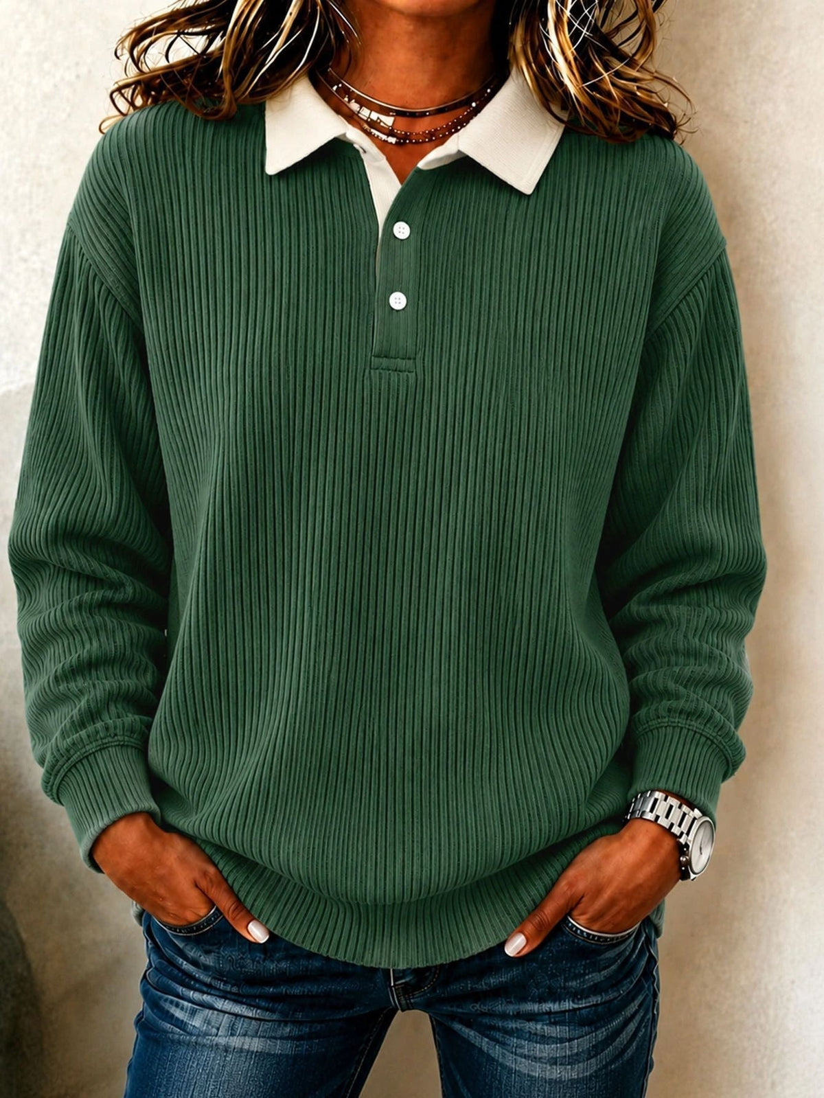 Polo verde oscuro de manga larga con superficie acanalada uniforme, cuello crema y botones claros.