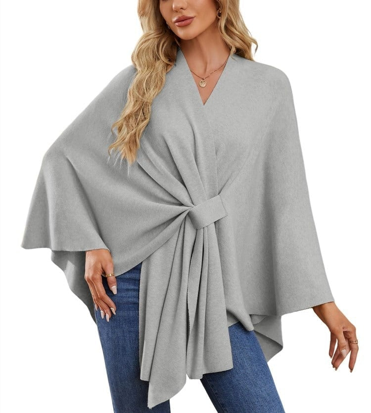 Poncho tipo chal gris claro con banda rectangular en el frente y un brazo extendido.