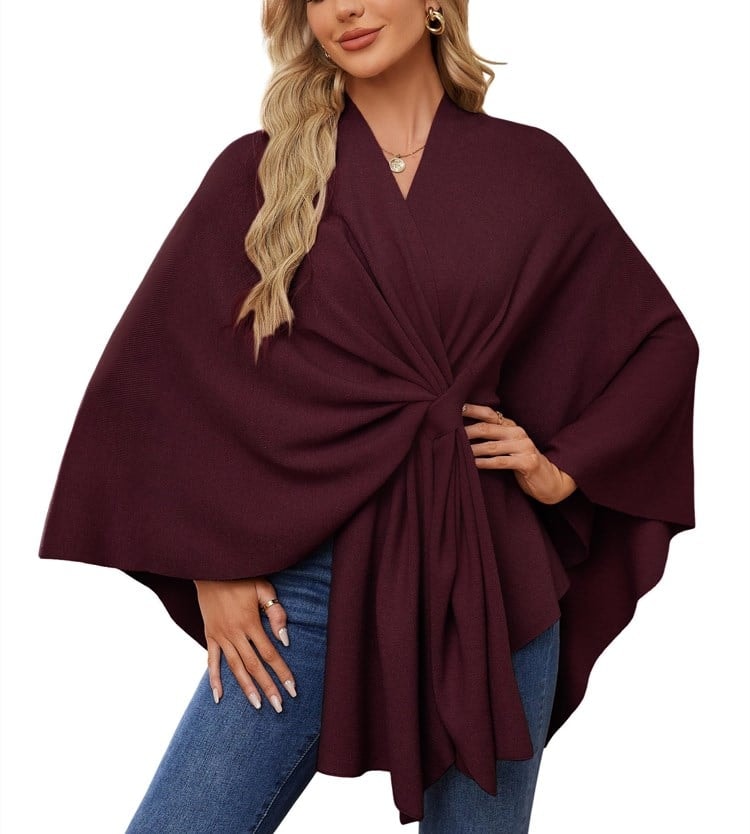 Poncho tipo chal burdeos con silueta envolvente, nudo frontal y mangas amplias.