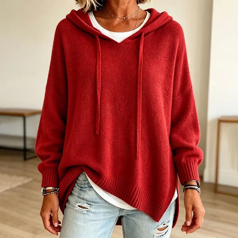 Sudadera roja con capucha y cordones, de corte relajado y bajo ligeramente asimétrico, combinada con vaqueros claros.