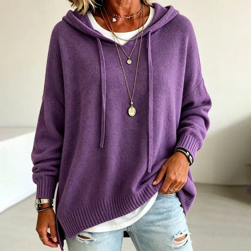 Sudadera morada con capucha y cordones, de corte relajado, combinada con vaqueros desgastados y camiseta blanca visible.