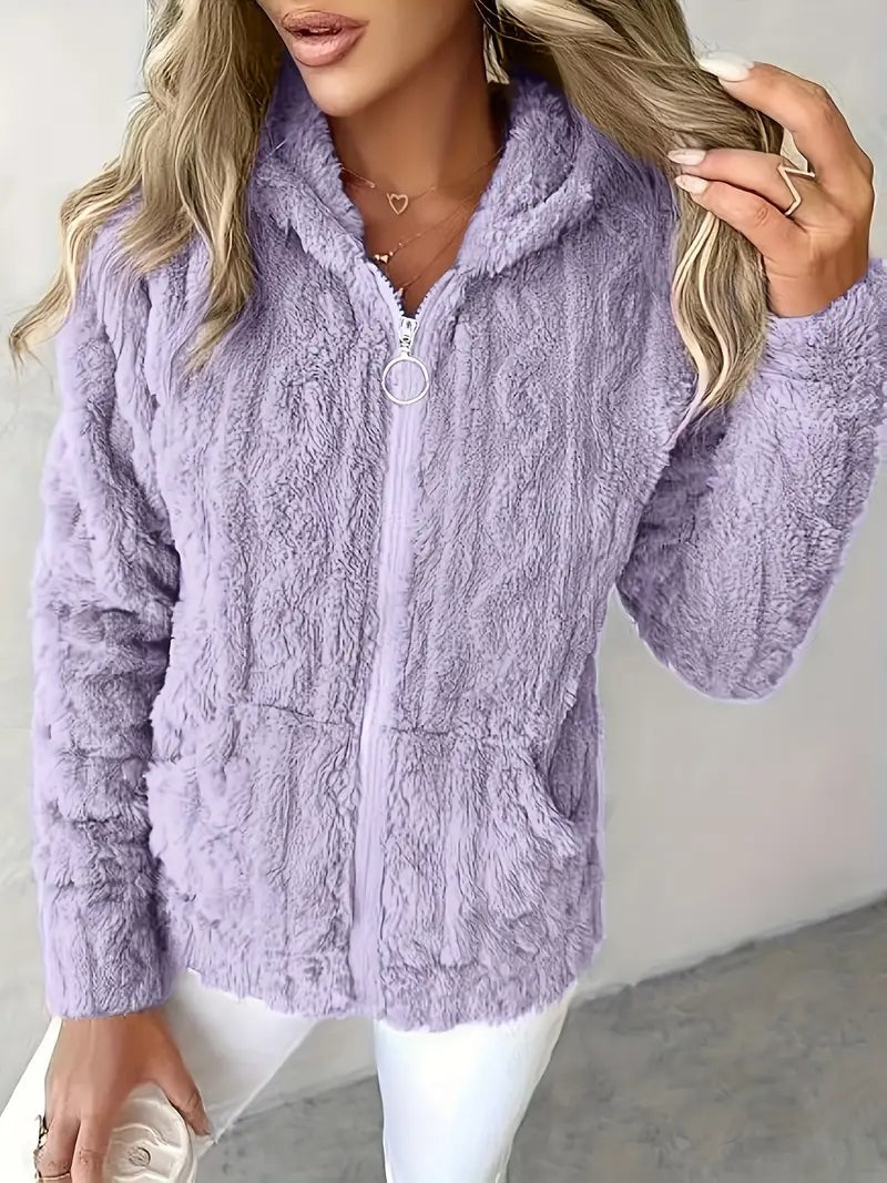 Sudadera con capucha lila de textura suave, cremallera frontal con tirador circular y bolsillos delanteros, combinada con pantalón blanco.
