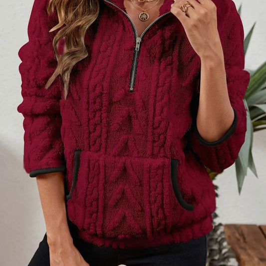 Sudadera burdeos de cuello alto con cremallera parcialmente abierta, textura en relieve y bolsillo canguro.