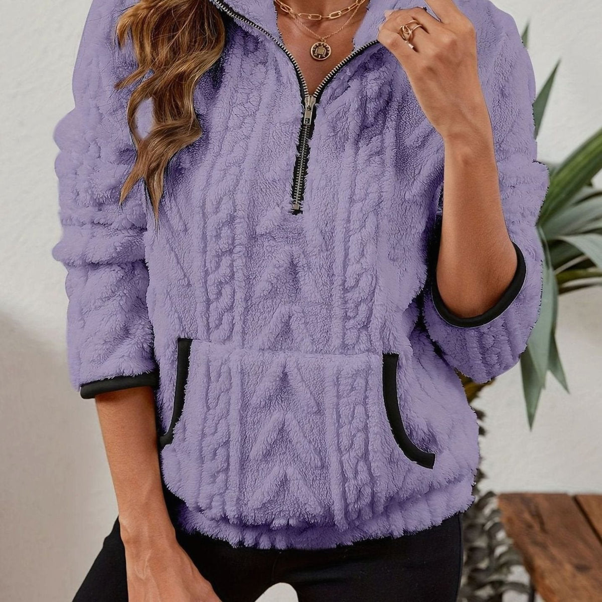 Sudadera lila de textura en relieve con cuello alto, cremallera frontal y bolsillo canguro.