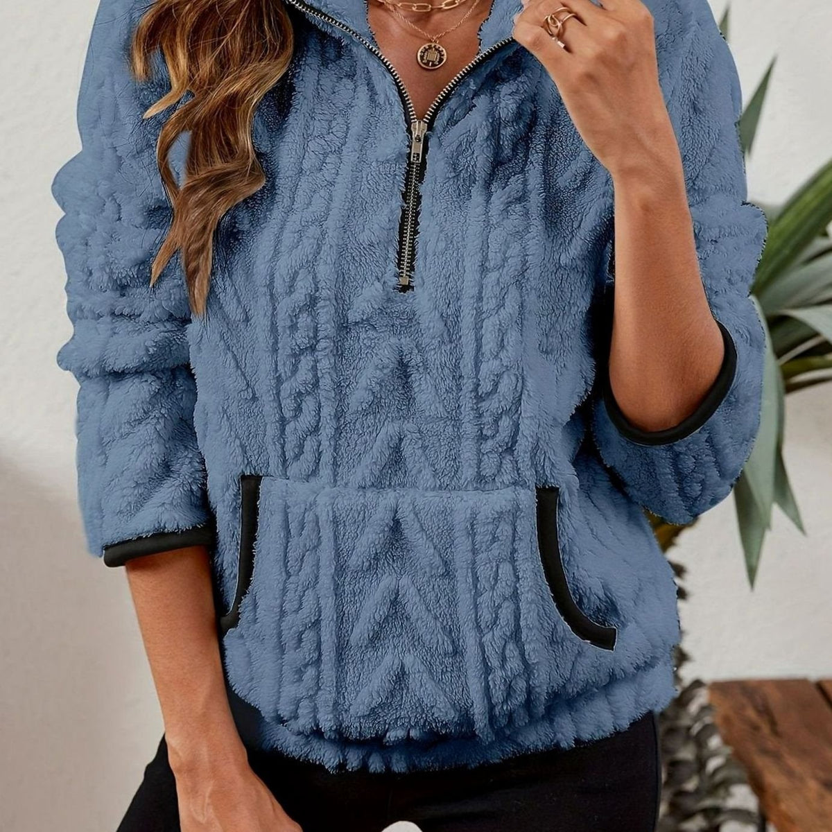 Sudadera azul con cuello alto y cremallera frontal, textura en relieve y bolsillo canguro.