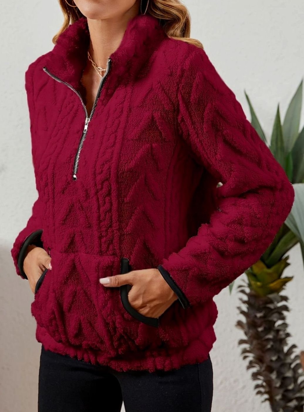 Sudadera burdeos mostrada de lado, con la cremallera delantera abierta y las manos en el bolsillo canguro.