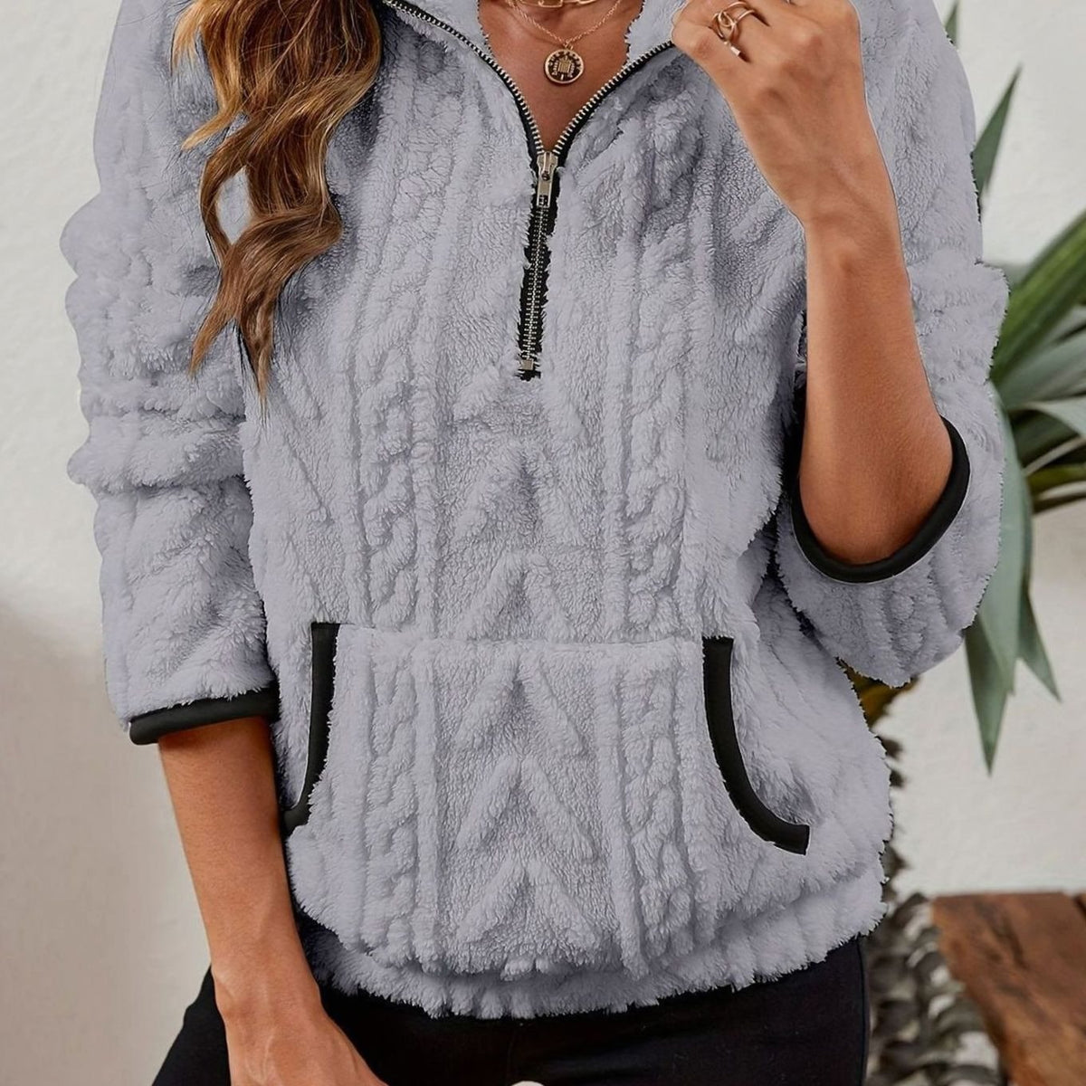 Sudadera gris claro con cuello alto, cremallera corta, textura en relieve y bolsillo canguro.