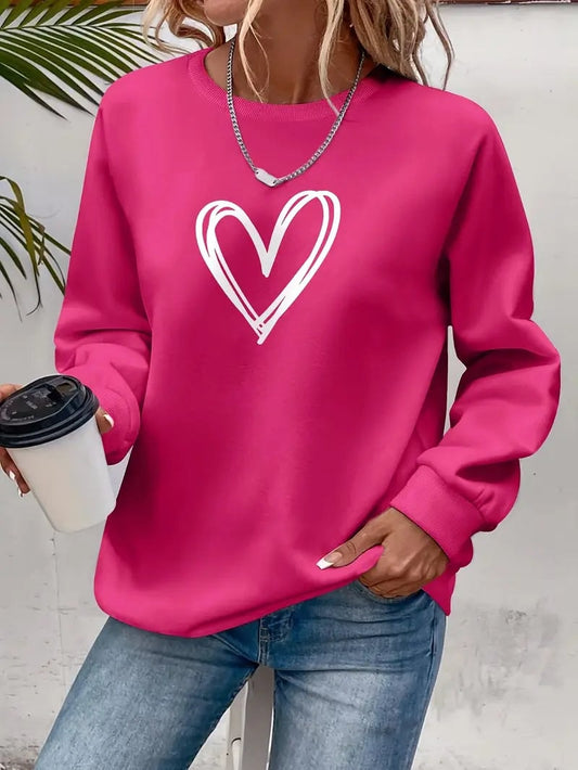Sudadera fucsia de cuello redondo, mangas largas con puños y corazón blanco dibujado en el pecho, llevada con vaqueros.