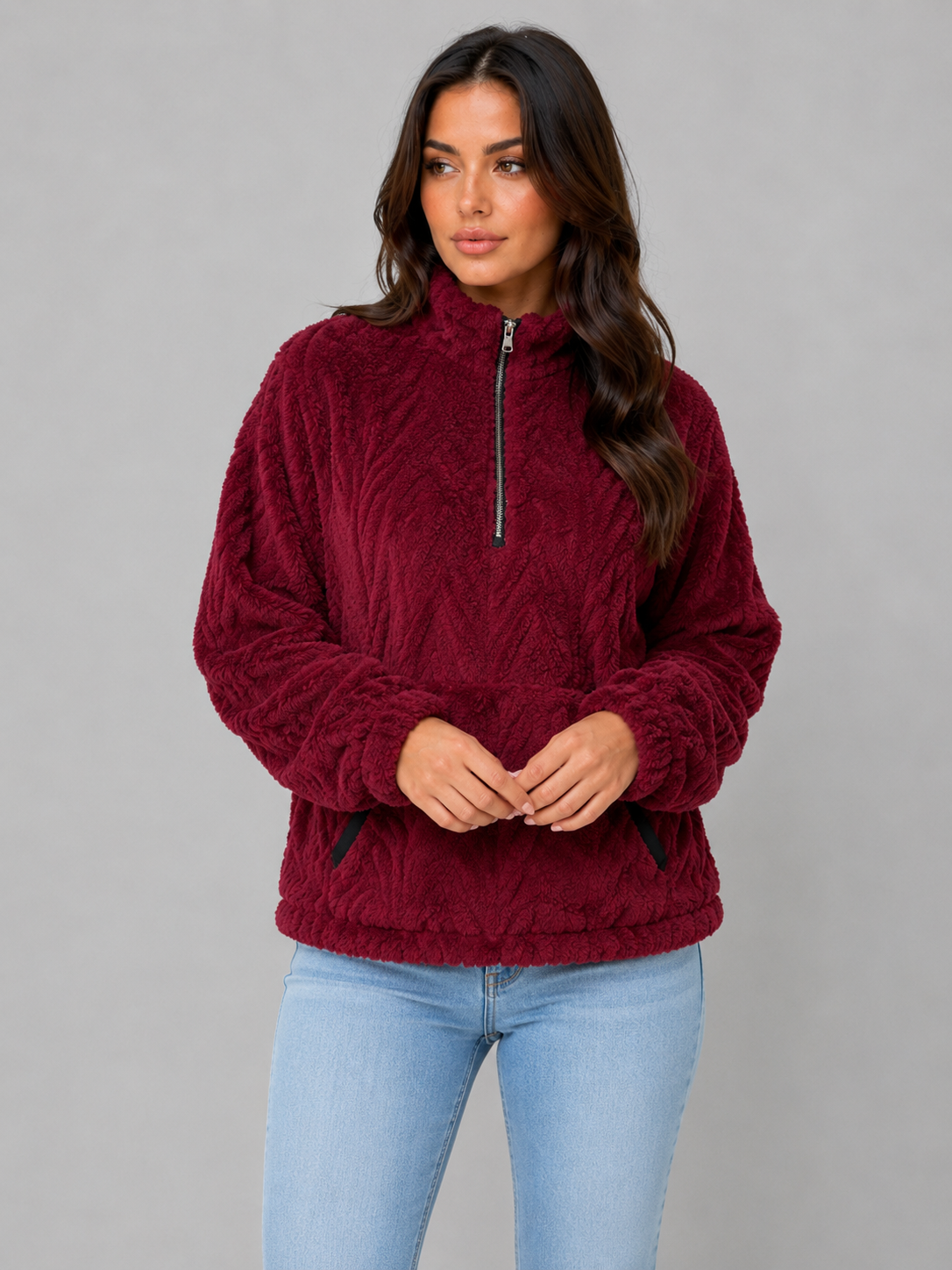 Sudadera burdeos de pelo con cuello alto y media cremallera, mostrada de frente con las manos juntas.
