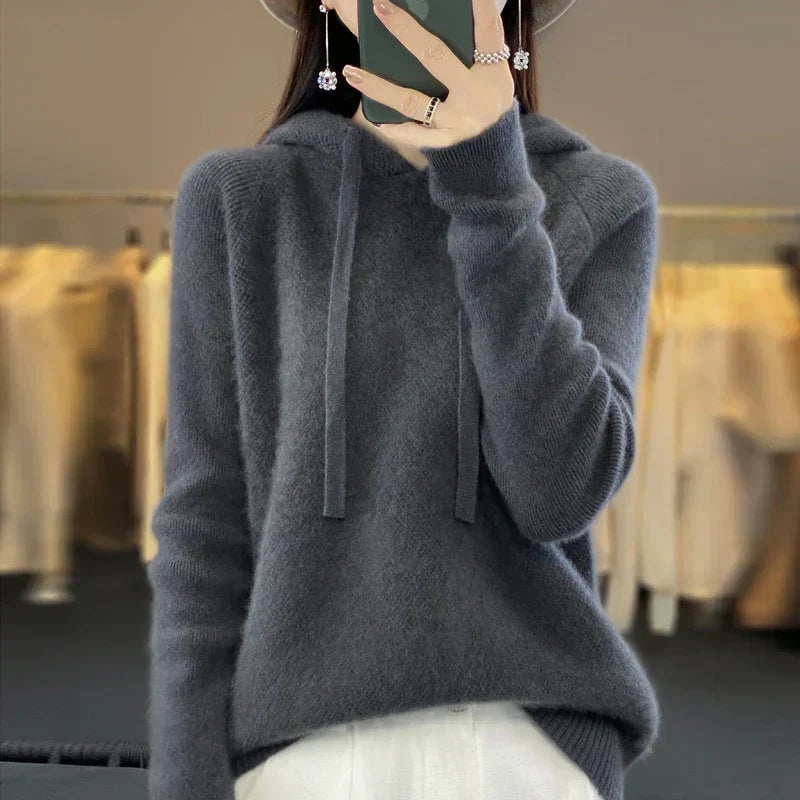 Sudadera de punto oversize gris antracita con capucha y cordones, combinada con pantalón blanco.