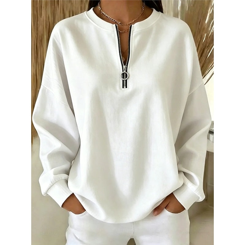 Sudadera holgada blanca con cuello redondo, media cremallera y tirador de aro, combinada con pantalón blanco.