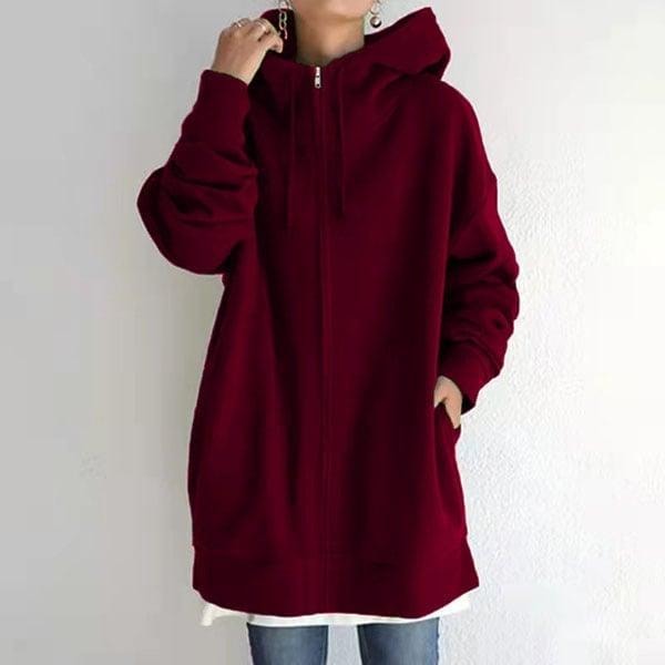 Sudadera oversize rojo intenso con capucha y cremallera frontal, llevada sobre una prenda blanca.