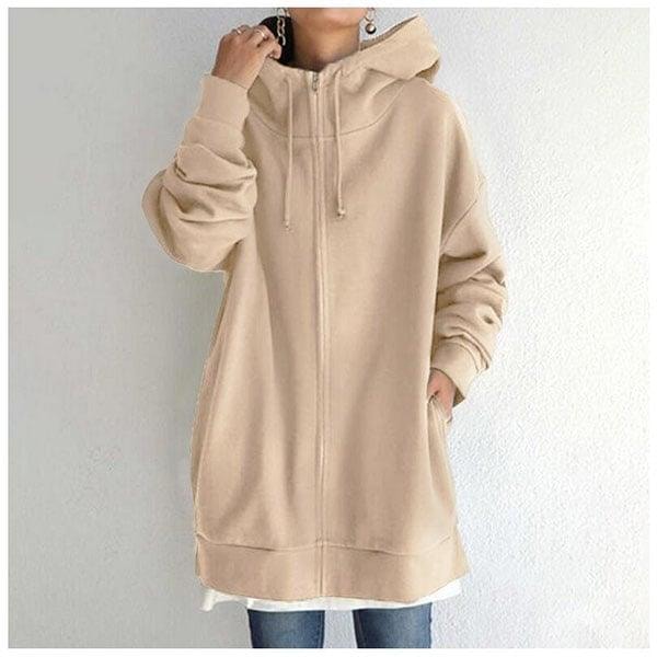 Sudadera oversize beige claro con capucha, cremallera frontal y bolsillos laterales, llevada sobre una prenda blanca.