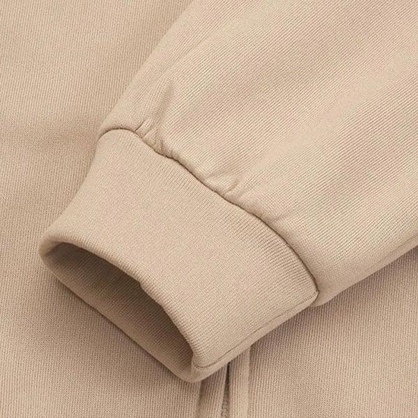 Detalle cercano del puño acanalado y la costura de la manga de la sudadera beige.