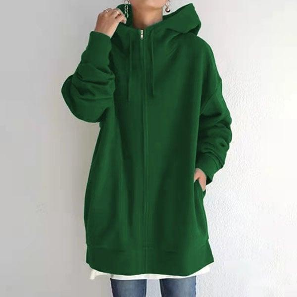 Sudadera oversize verde con capucha y cordones, cremallera frontal y bolsillos laterales, combinada con vaqueros.