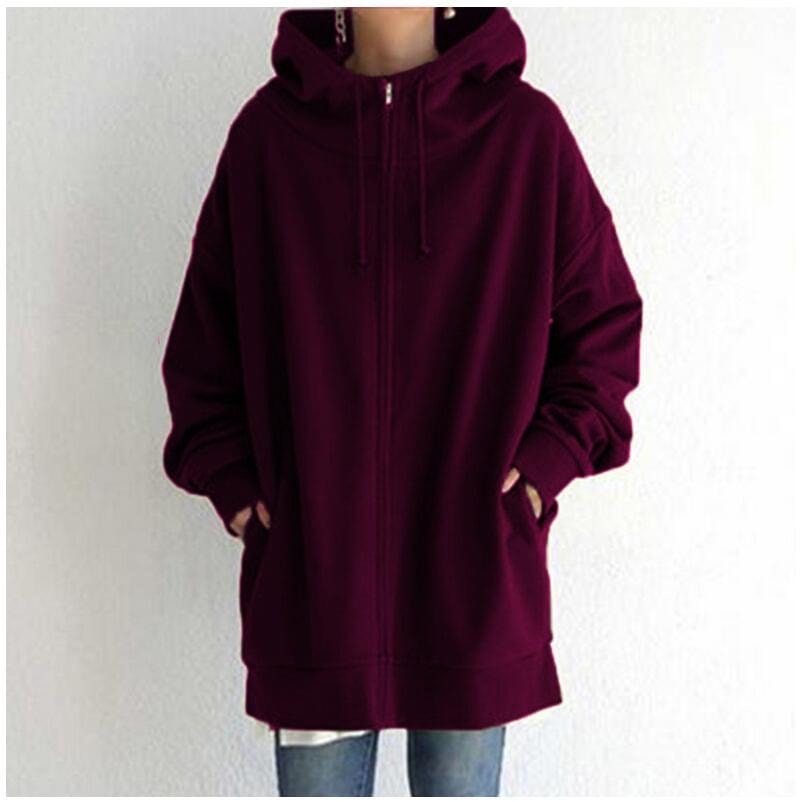 Sudadera oversize burdeos oscuro con cremallera frontal y capucha, presentada con las manos en los bolsillos.