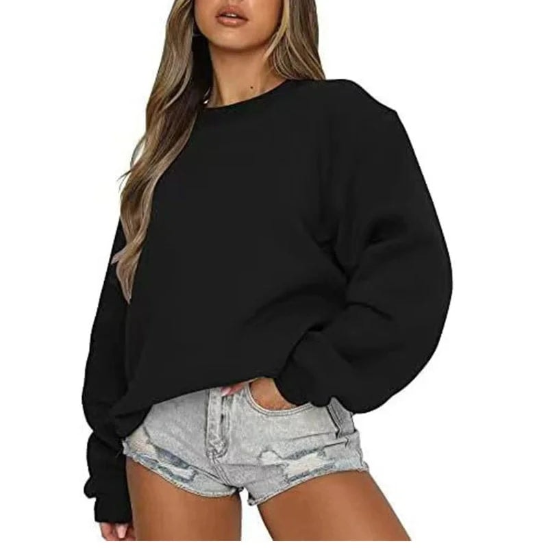 Sudadera oversize negra de cuello redondo y mangas amplias, combinada con shorts vaqueros claros.