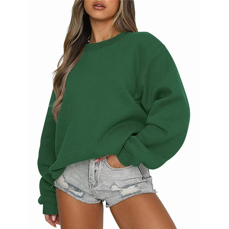 Sudadera oversize verde oscuro con cuello redondo y bajo ajustado, acompañada de shorts vaqueros.