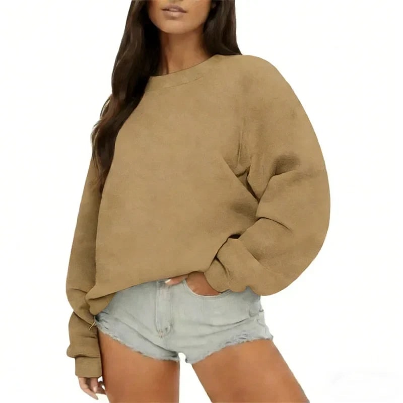 Sudadera oversize beige de cuello redondo y mangas voluminosas, combinada con shorts claros.