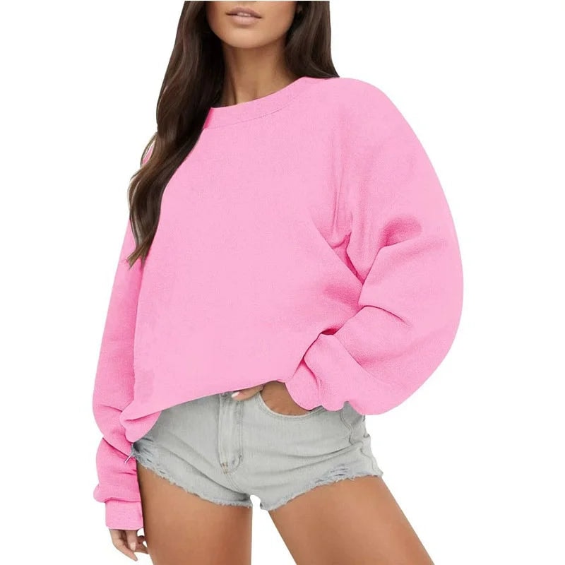 Sudadera oversize rosa intenso con puños ajustados y bajo recogido, sobre shorts vaqueros.