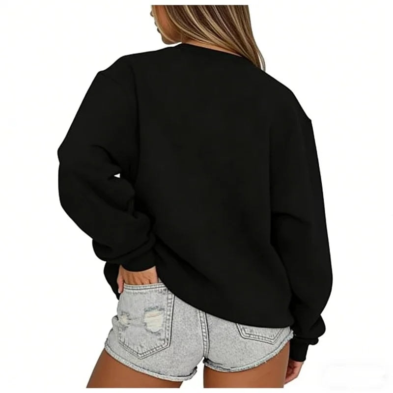 Vista trasera de la sudadera oversize negra, con bajo y puños ajustados sobre shorts vaqueros.