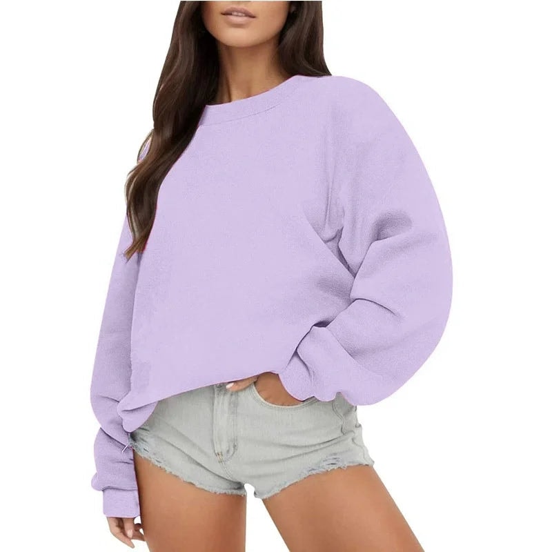 Sudadera oversize lila de cuello redondo y silueta desenfadada, combinada con shorts claros.