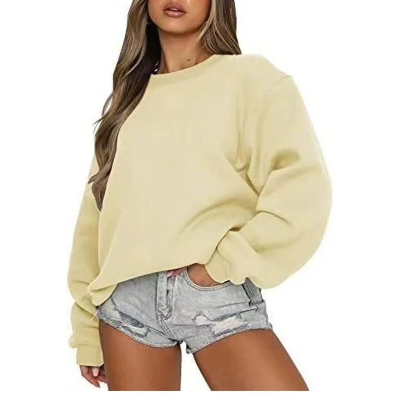 Sudadera oversize amarilla pálida con mangas amplias y bajo ajustado, sobre shorts vaqueros.