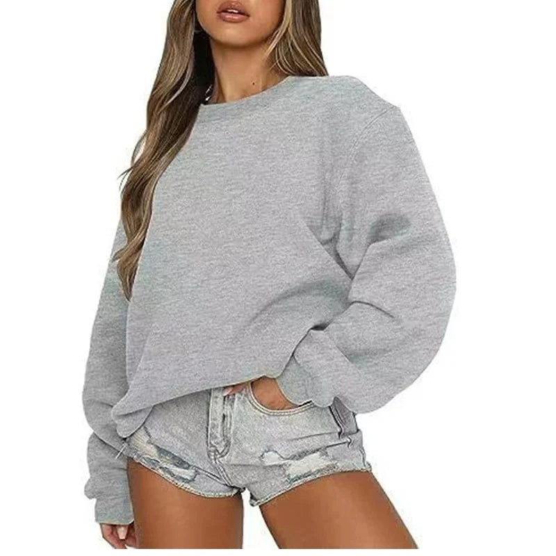 Sudadera oversize gris jaspeado con mangas amplias y puños ajustados, combinada con shorts vaqueros.