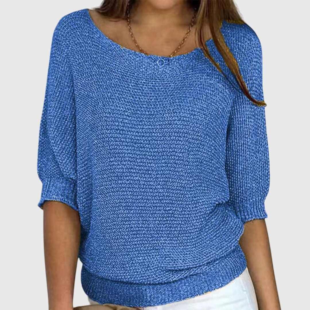 Suéter holgado azul de escote amplio y mangas tres cuartos, combinado con pantalón claro.