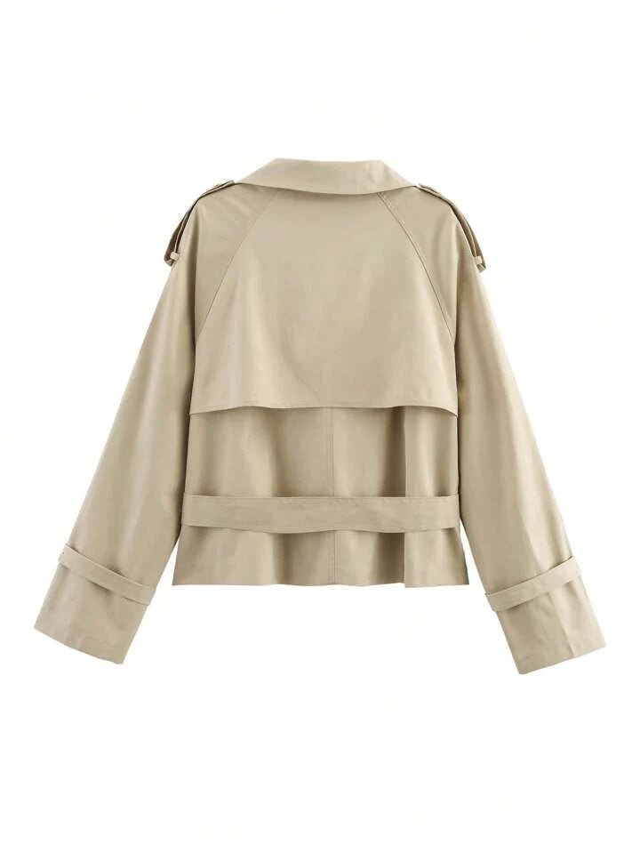 Vista posterior del trench corto beige, con pieza superpuesta en la espalda, cinturón trasero y trabillas en los hombros y puños.