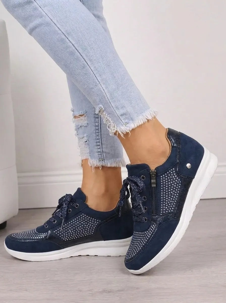 Vista lateral de las zapatillas azul marino, que muestra la cremallera exterior, los cordones y la suela blanca elevada.
