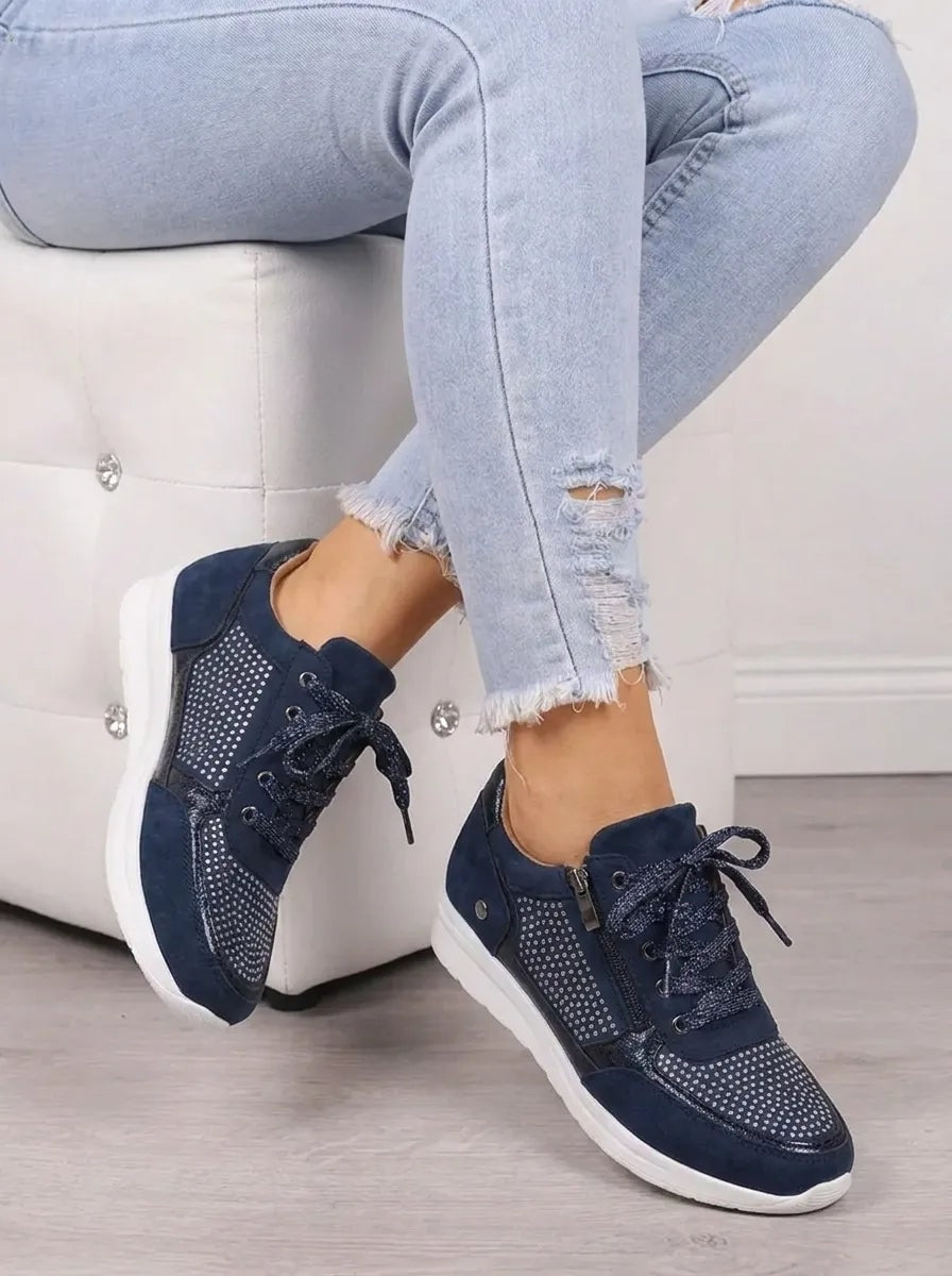 Zapatillas casual azul marino vistas en diagonal mientras se llevan sentada, con paneles decorativos y cierre de cordones.