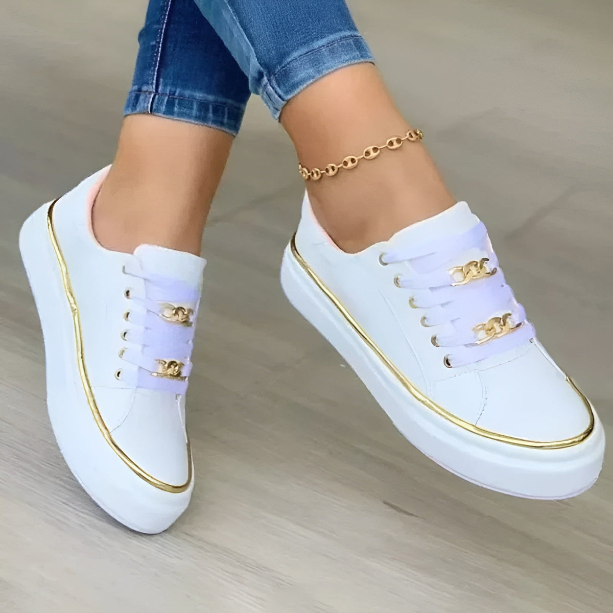 Zapatillas blancas de plataforma con cordones y detalles metálicos dorados, vistas desde arriba mientras se llevan con vaqueros.