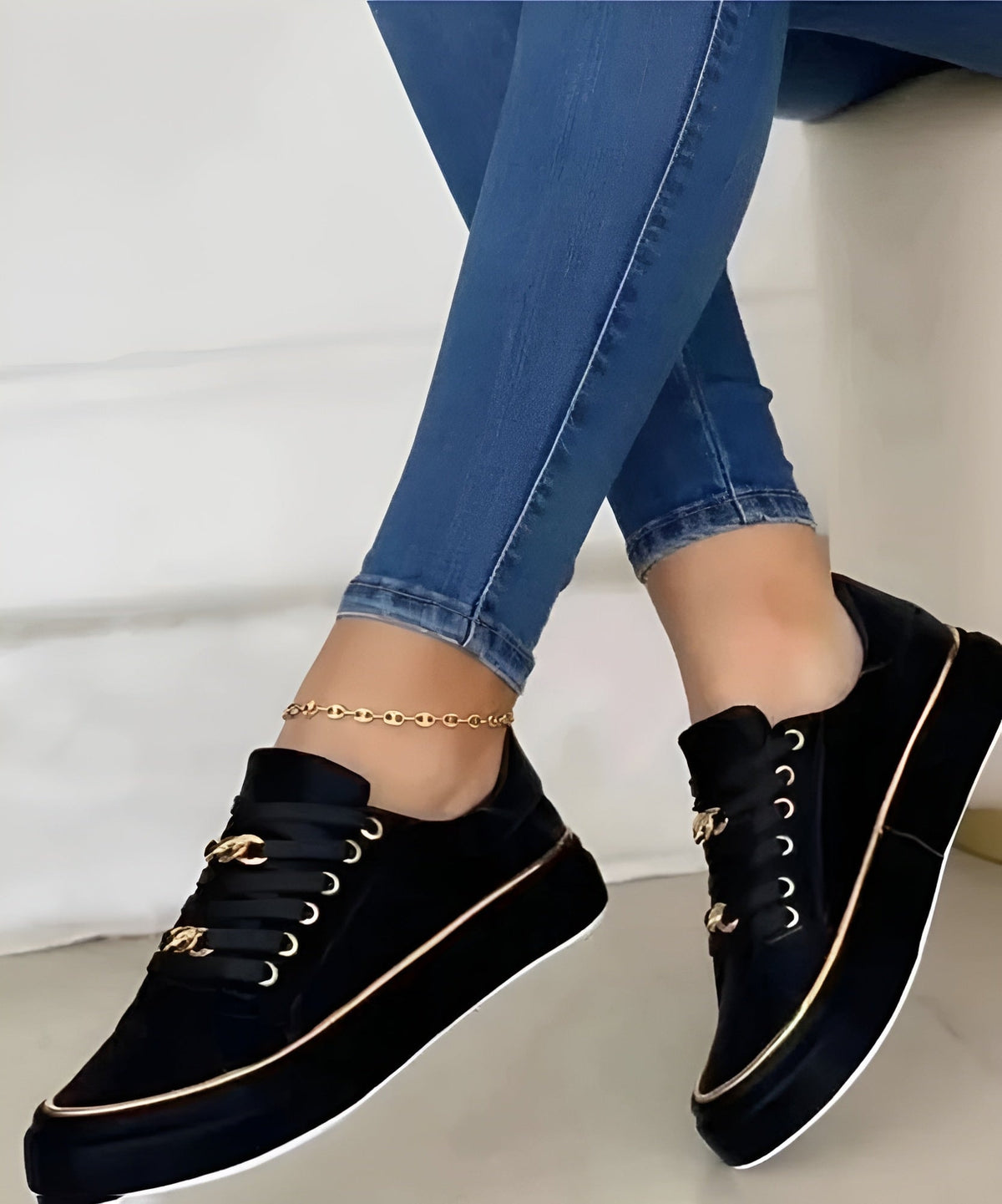 Zapatillas negras de plataforma con cordones, ojales dorados y ribete metálico, mostradas de perfil con los pies cruzados.